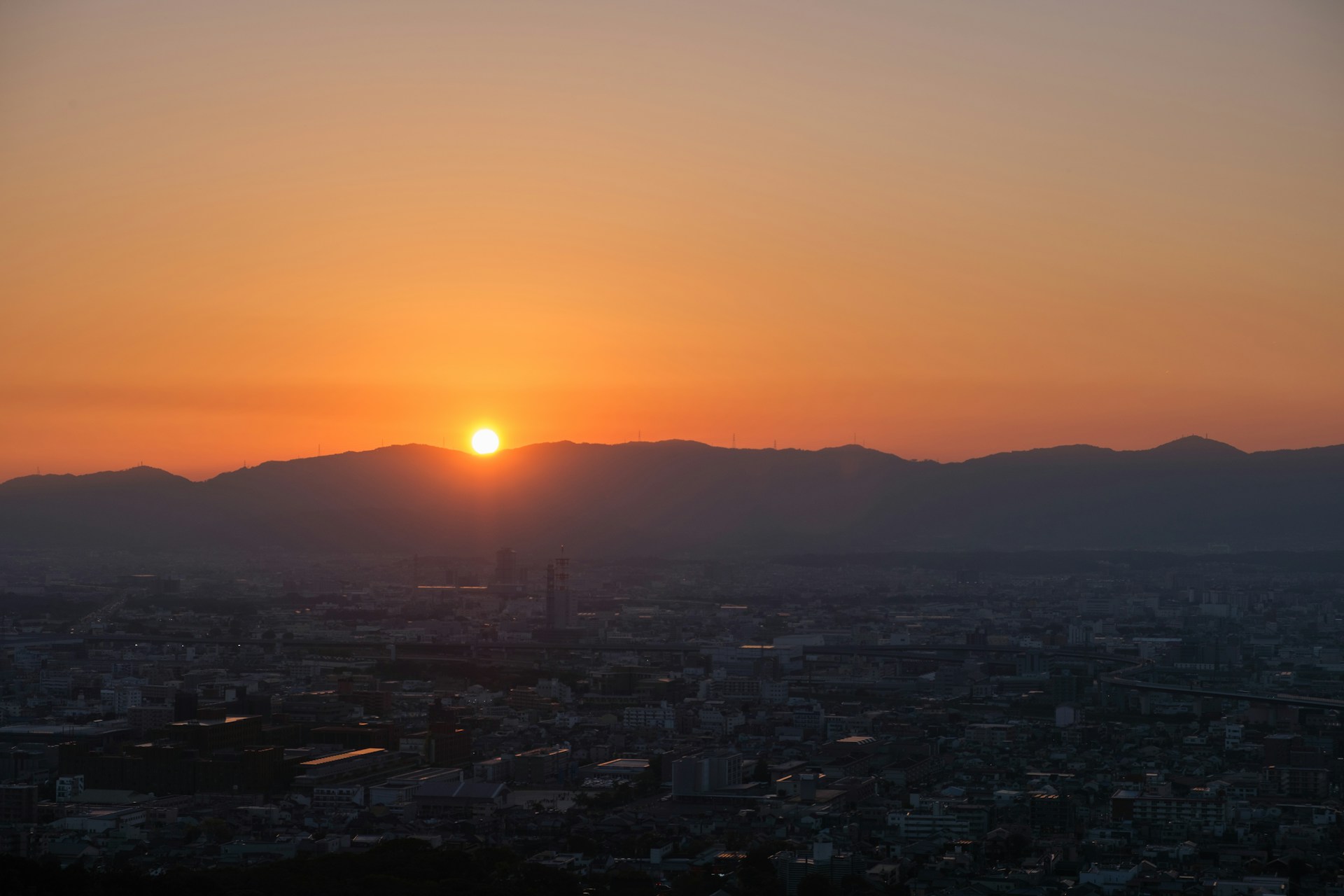 山並みに沈む夕日と街の風景